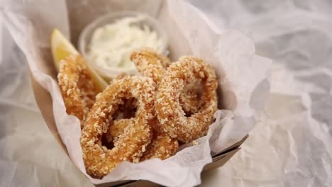 crispy fried squid rings in a box with lemon and dip