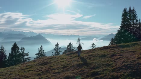 guy walking on a mountain ridge looking into beautiful mountain scenery with fog covered lake sunny swiss alps rigi