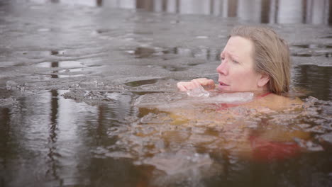 Woman-taking-ice-bath-in-icy-lake-in-winter,-therapeutic-health-benefits