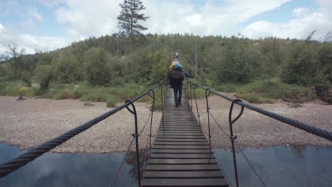 person hiking across a wooden suspension bridge in a forest