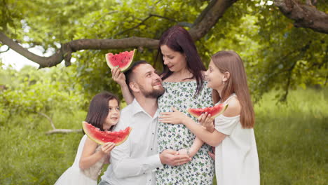 family enjoying watermelon picnic in a park