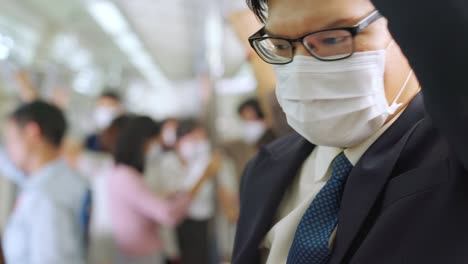 young man wearing face mask travels on crowded subway train