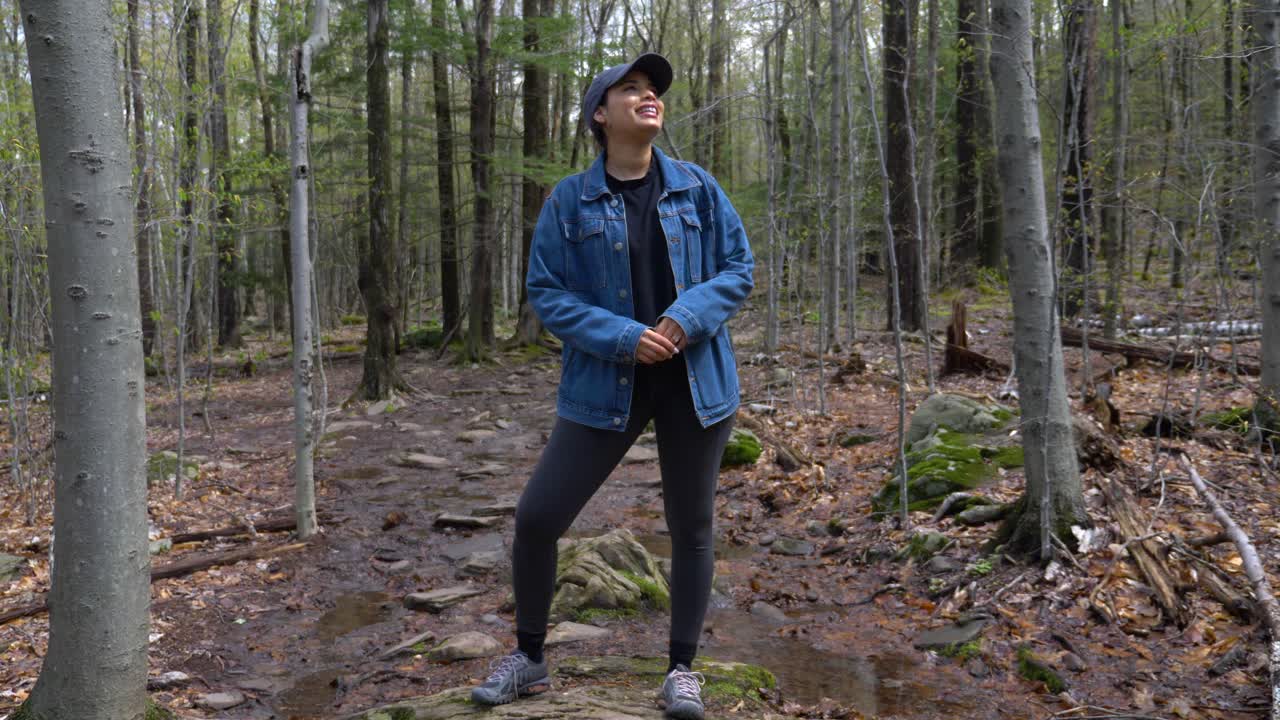 Ung, glad og vakker kvinne som smiler bredt og nyter sollyset utendørs på en solrik tursti i Upstate NY.