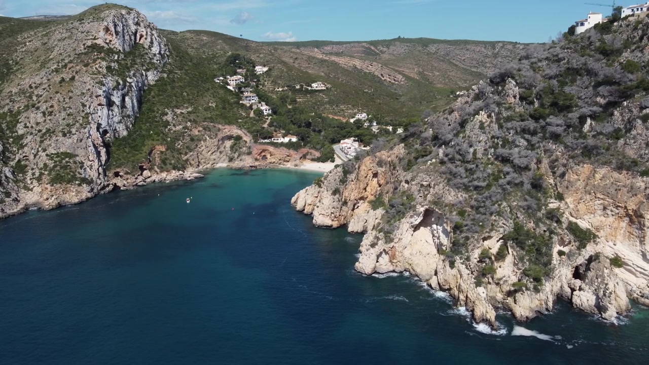 Letecký záběr odhalující pláž Granadella s rackem letícím před kamerou. Javea, Španělsko.