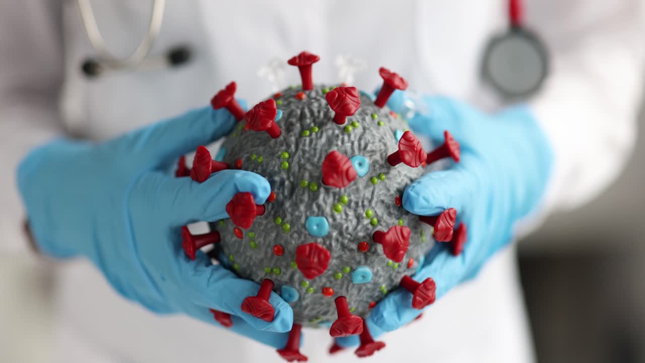 Médico con guantes de goma sosteniendo un modelo artificial de coronavirus, primer plano, película 4K en cámara lenta.