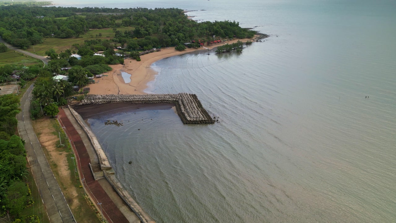 Aerial view of peaceful tropical island coastline with a breakwater, lush greenery, and stunning waters - San Lorenzo, Guimaras, Philippines