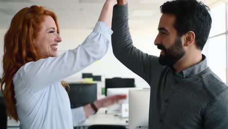 two colleagues share a joyful moment in a bright office space, showcasing teamwork and camaraderie. laughter and smiles fill the atmosphere as they celebrate their achievement together.