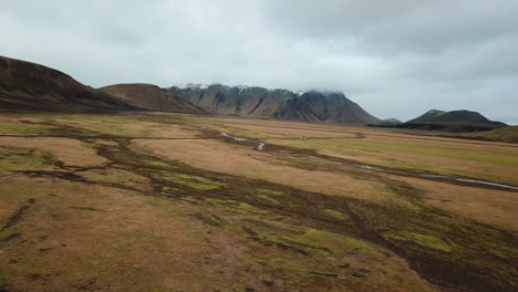 highlands of iceland. pull back aerial view of landscape, valley under volcanic hills and cloudy sky