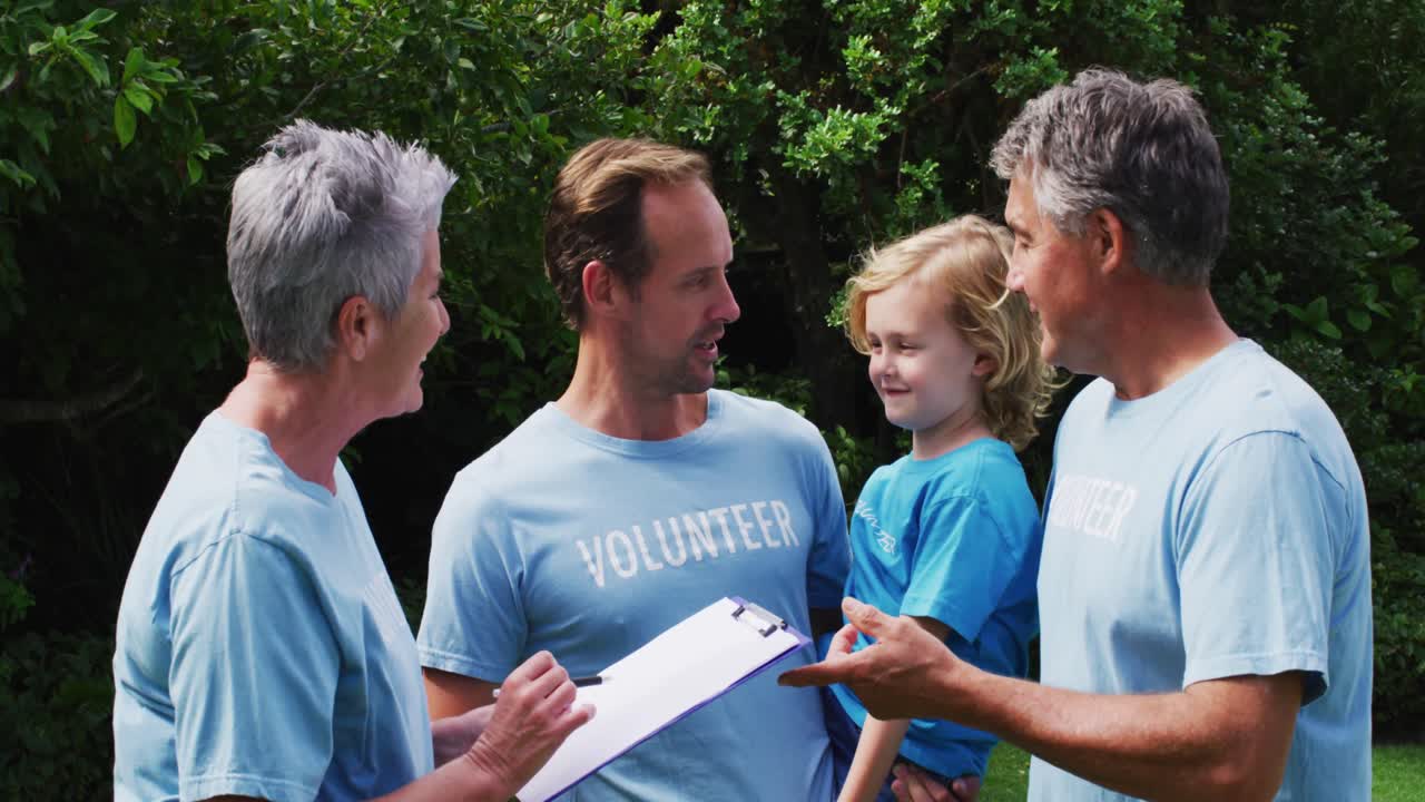 백인 노인 부부 와 아버지 와 아들 은 자원 봉사자 티셔츠 를 입고  ⁇  에서 이야기 하고 있다