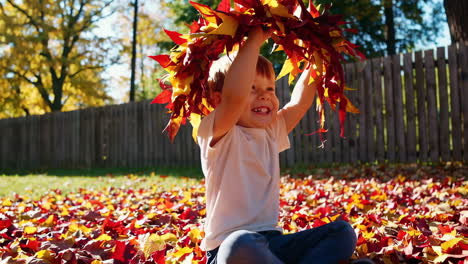 child playing with fall leaves