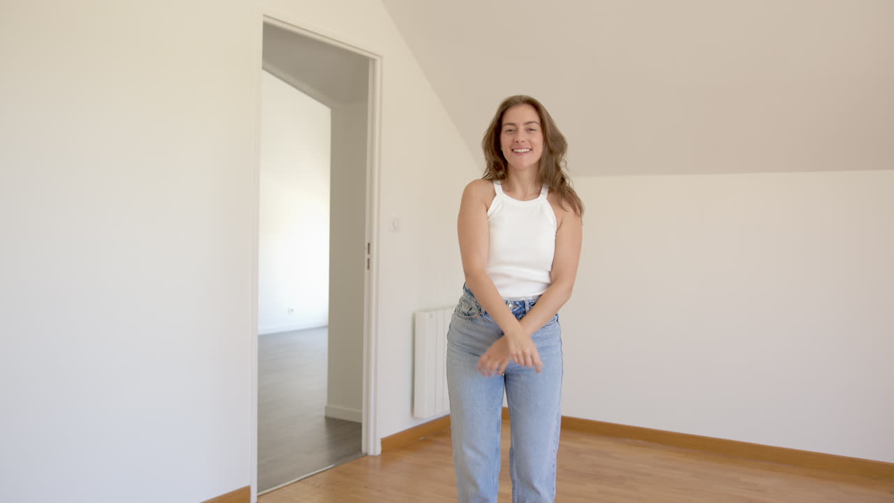 Happy woman inside her new empty apartment, dance of joy