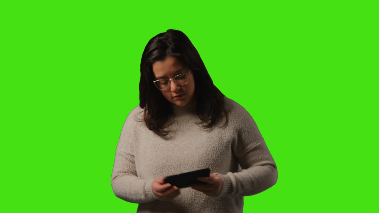 joven respondiendo a una llamada en el teléfono móvil de pie contra el fondo del estudio de pantalla verde