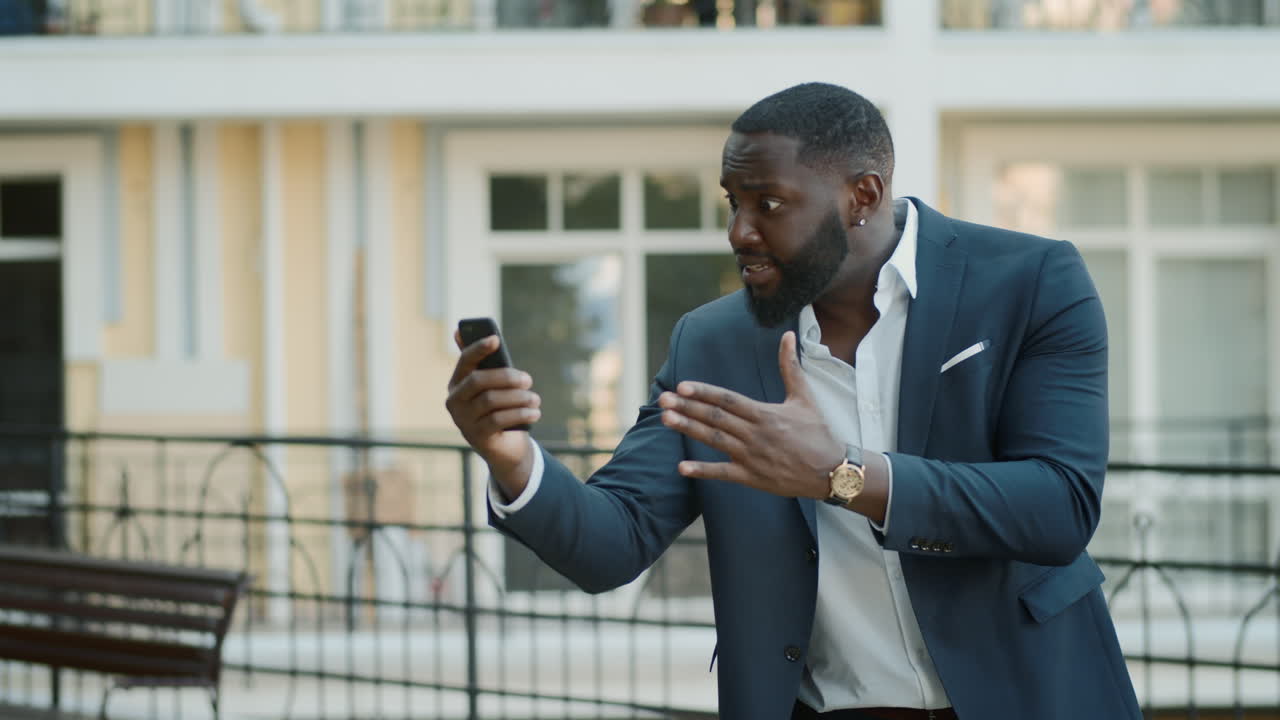 Angry businessman having video chat at urban street
