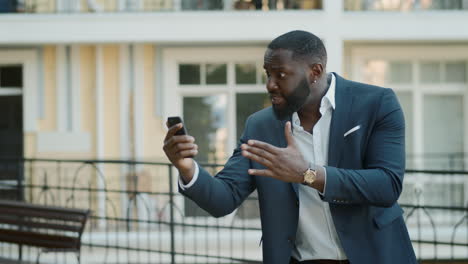 angry businessman having video chat at urban street