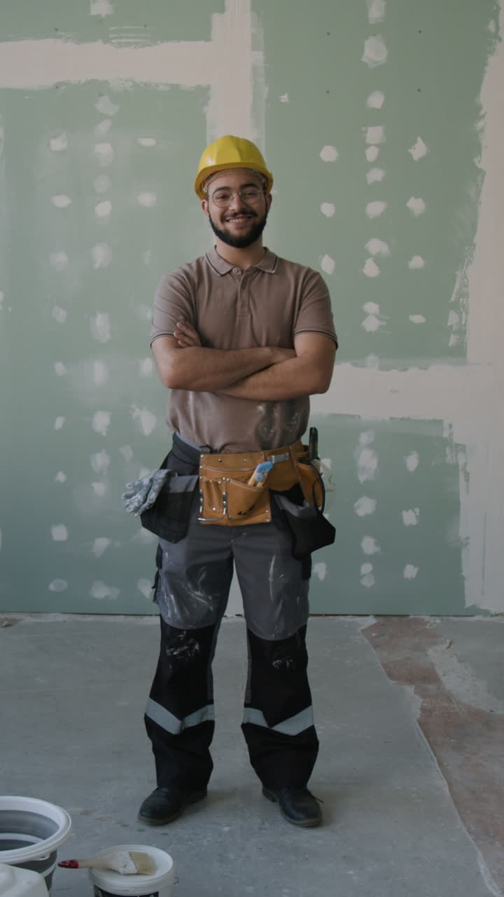 Construction worker with arms crossed in front of drywall