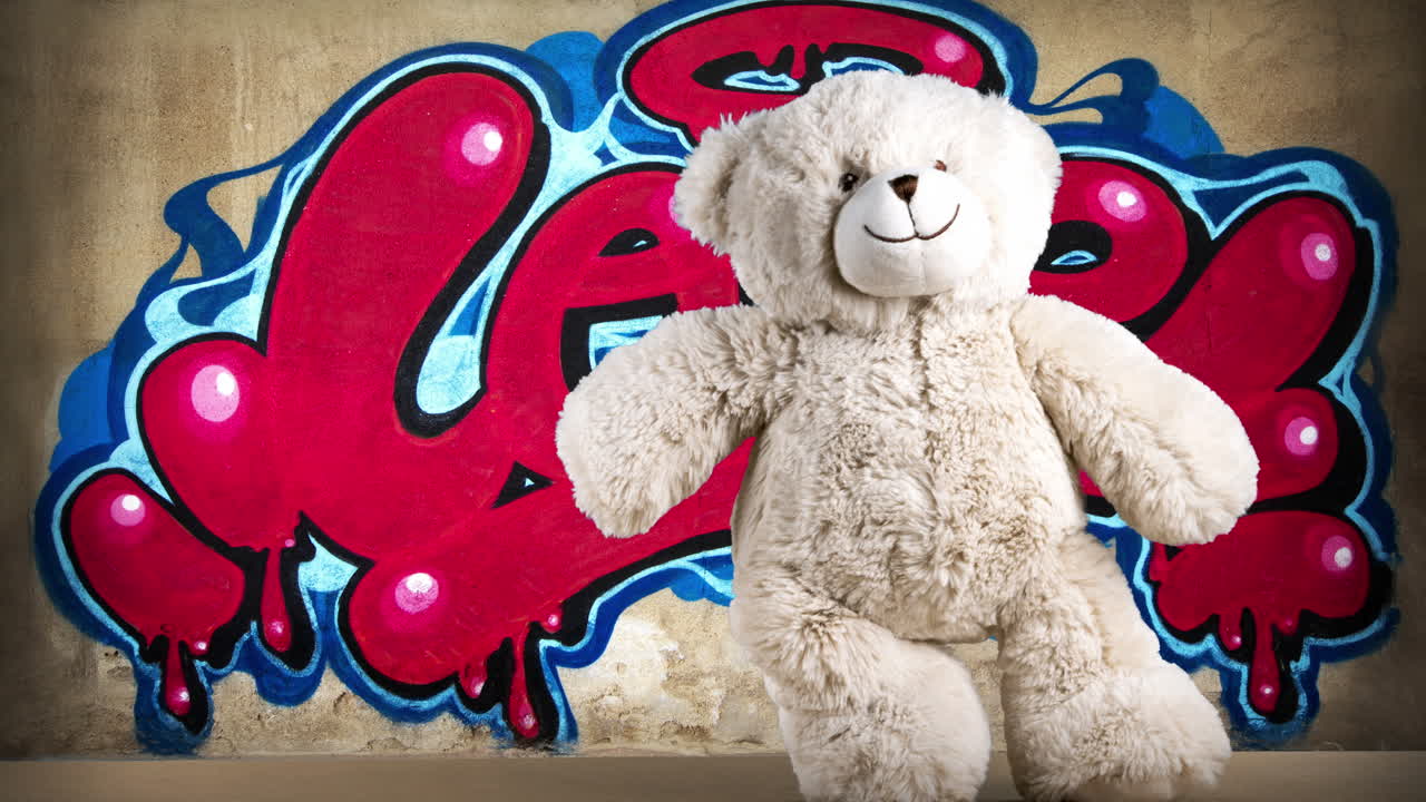 oso de peluche frente a la pared de graffiti