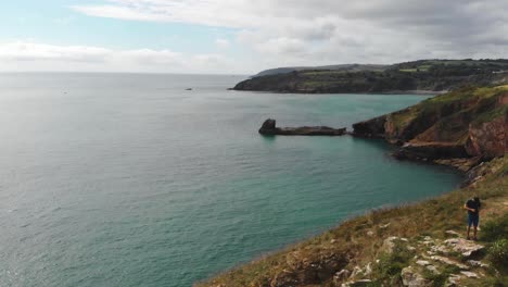 Aerial-view,-adventurer-on-a-cliff,-ocean-background,-Dorset,-England,-traveling-shot,-drone