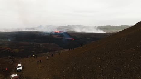 aerial landscape view of many people looking at the volcanic eruption at litli-hrutur, iceland, with lava and smoke coming out