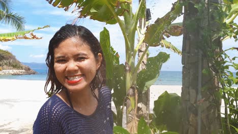 happy young woman enjoys outdoor shower on a beach smiling and being playful.