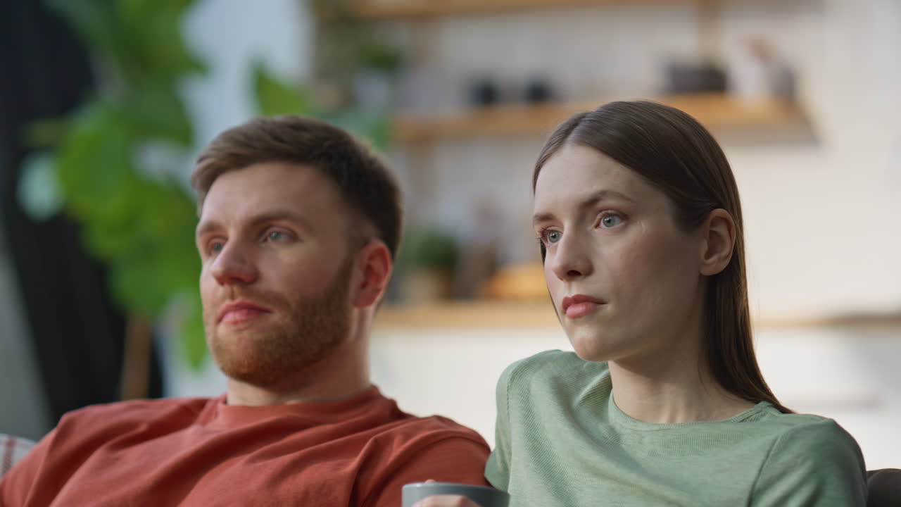 Resting spouses switching channels looking favorite show at home couch closeup