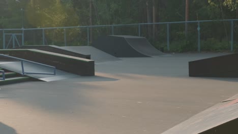 young man in sweatshirt and jeans practicing skateboarding in skate park