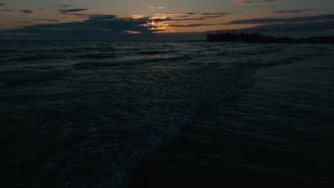 Waves-crashing-at-Owen-Sound,-Ontario-during-a-moody-sunset-with-dark-waters-and-sky