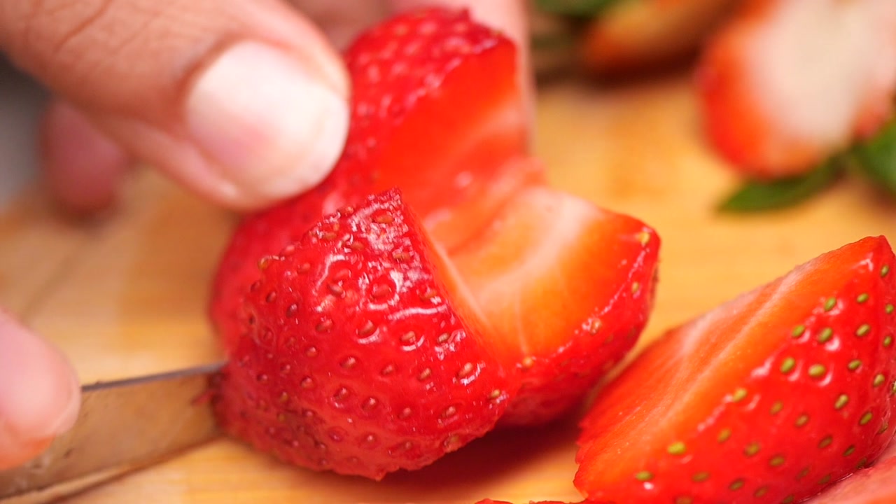 Close-up of Hand Cutting Fresh Strawberry on Wooden Board