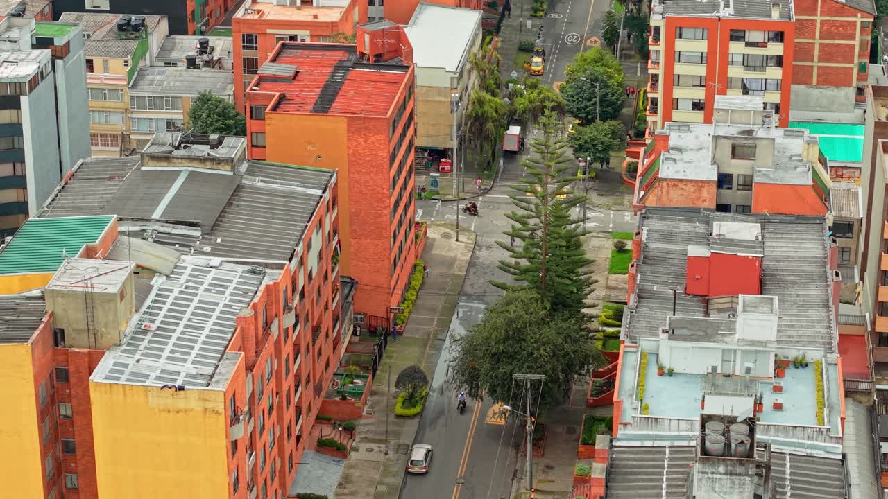 Vista aérea de drone de Bogotá, Colômbia, com casas alaranjadas entre ruas verdes arborizadas.