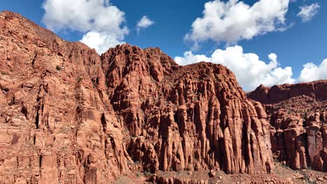 Acantilados-De-Rocas-Rojas-En-La-Vista-Aérea-Del-Desierto-Con-Cielo-Azul-Y-Nubes-Blancas-E-Hinchadas.