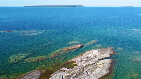 aerial flying over granite rocks poking through turquoise waters in georgian bay boarding ontario candaa