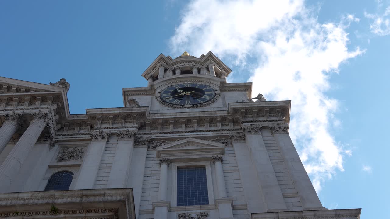 St Paul’s Cathedral in London showing the clock tower and facade from a low angle. Daytime view with architectural details and clouds in the sky