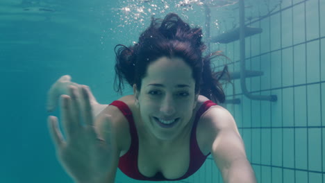 beautiful woman swimming underwater in pool smiling waving hand attractive female enjoying swim in clear water 4k