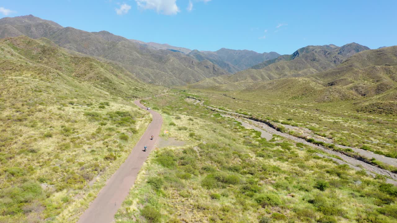 automóvil y dos motocicletas recorriendo un camino solitario en las montañas secas de mendoza