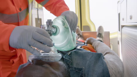 paramédico irreconocible que ayuda a un paciente estadounidense herido usando equipo respiratorio en la ambulancia