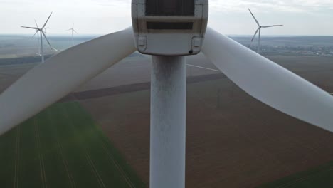 Rising with a drone behind a wind turbine, at the background with other wind turbines.