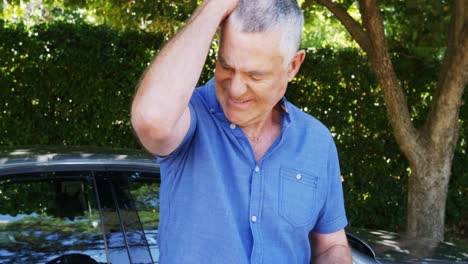 Senior-man-using-mobile-phone-near-car