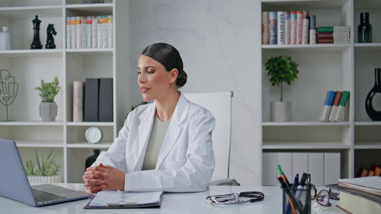 Clinic specialist consulting remotely using laptop camera at workplace closeup