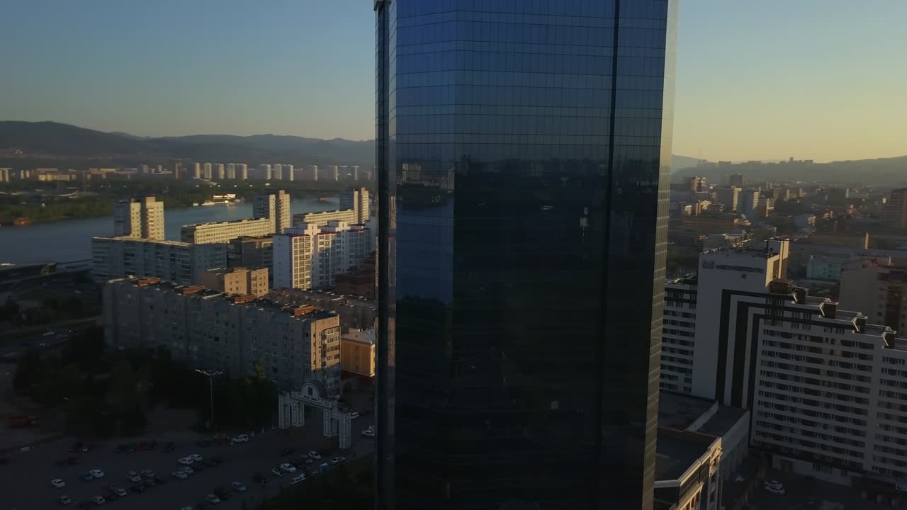 раунд-вью современного офисного здания, отражающего городской пейзаж красноярска.