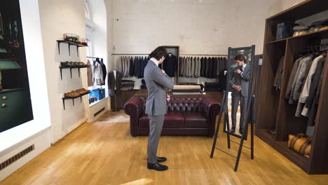 young man trying on suit in front of classy boutique mirror, zoom shot