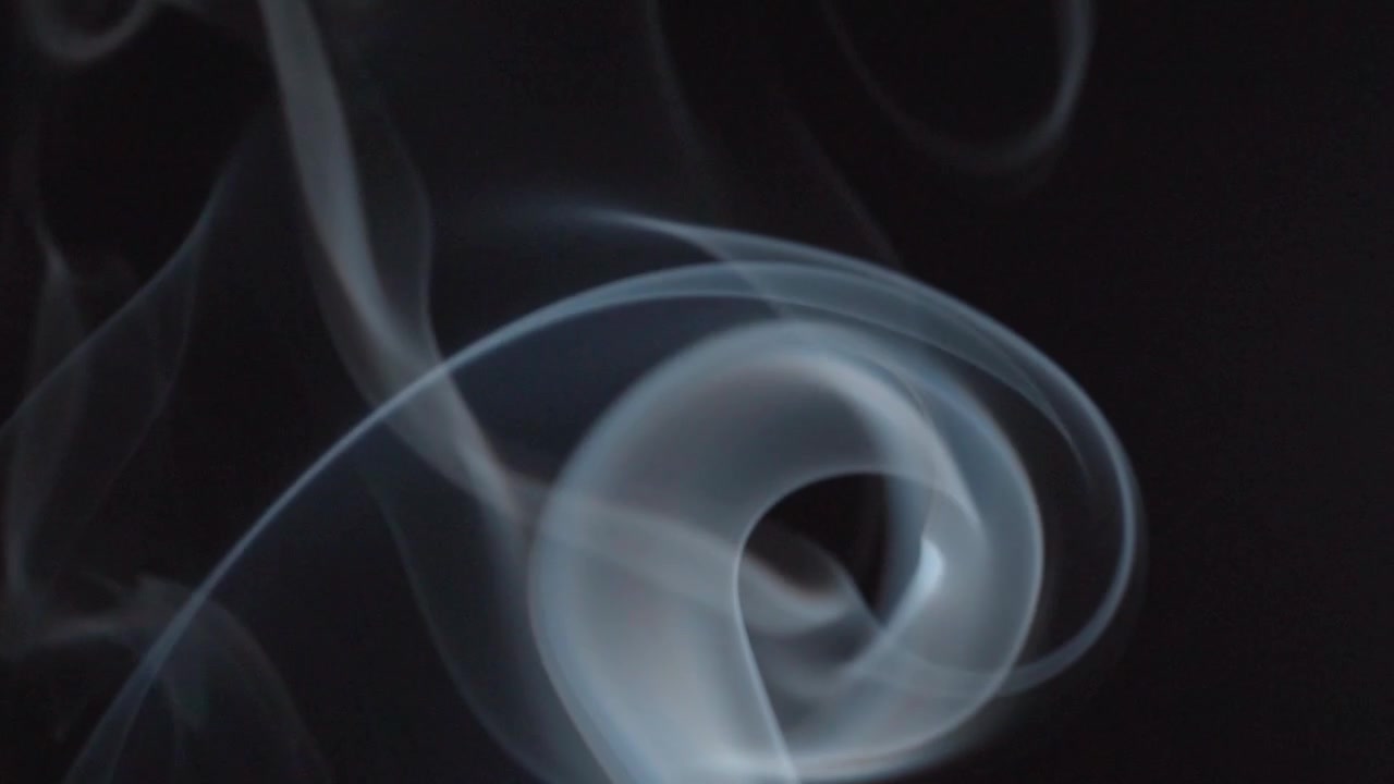 Macro view of swirling incense smoke creating abstract form against dark background, highlighting fluid movement, translucent layers, and delicate vapor details.