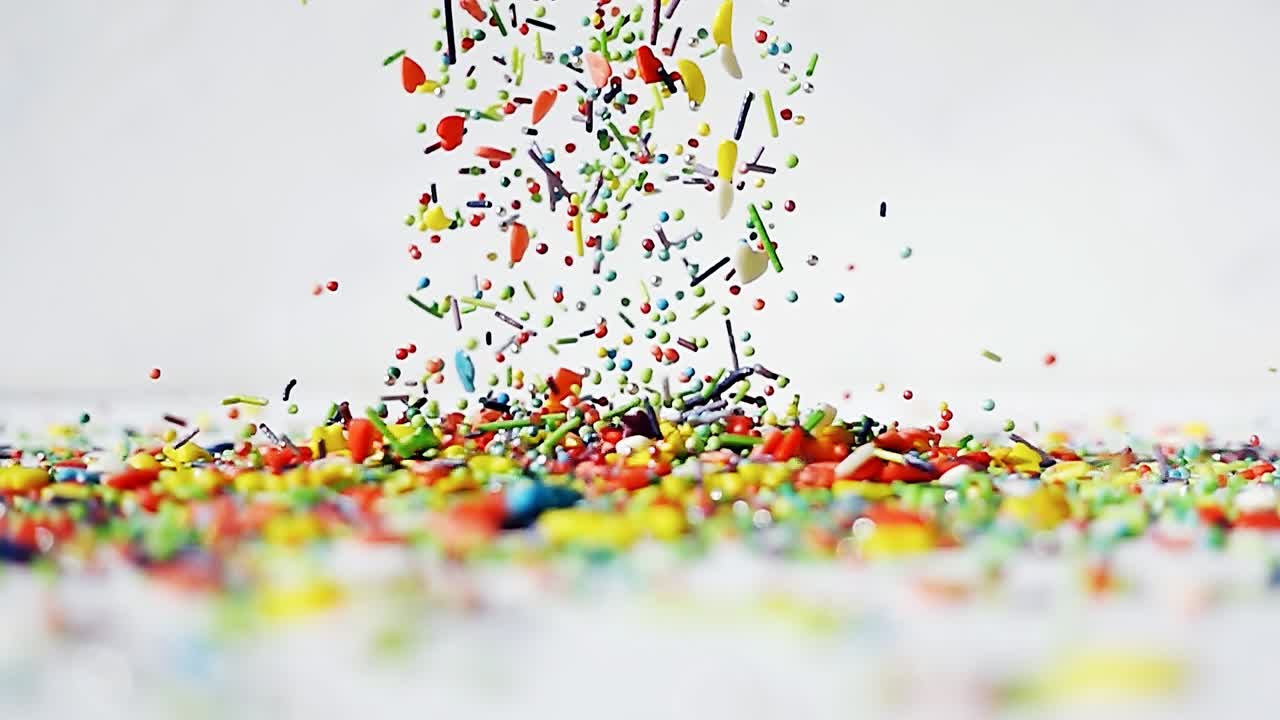 다채로운 모양의 달이가 색 바탕에 테이블 위에 떨어집니다. 4k 느린 동작 밝은 재미 비디오.