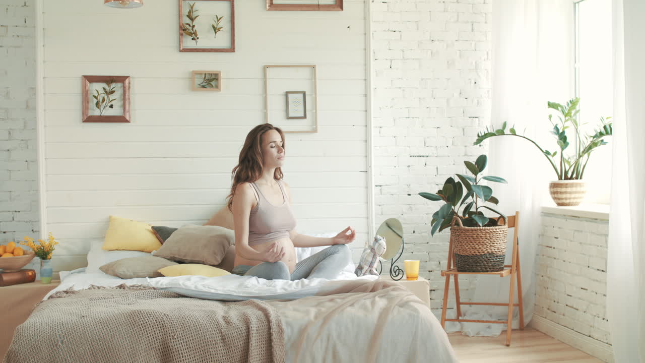 una mujer embarazada sana practicando yoga en la cama, una embarazada meditando en el interior.