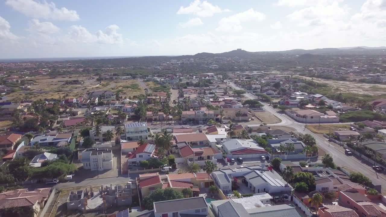 toma aérea de casas en aruba mientras los autos conducen por la carretera