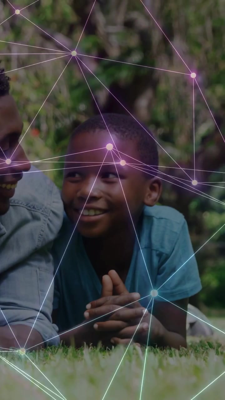 Vertical video: Dad leaning toward son sharing smile on lawn, tech overlay drifting over faces
