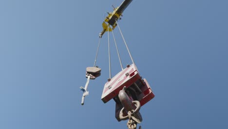 low angle upward view of a static lifting load crane and a sunny blue sky