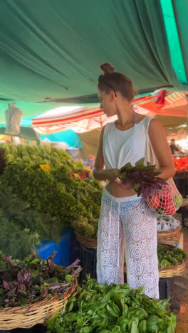 woman shopping for fresh herbs and vegetables at a market