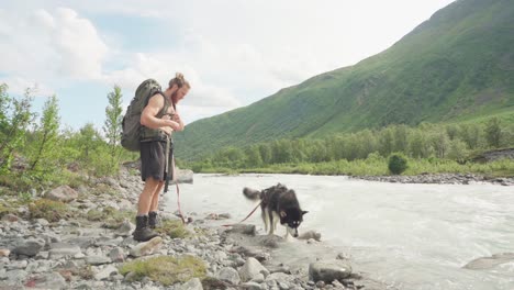 Male-Backpacker-With-A-Dog-Stops-From-Walking-Cools-His-Body-With-Water-From-A-Rocky-River-In-Lyngsdalen-Valley,-Norway