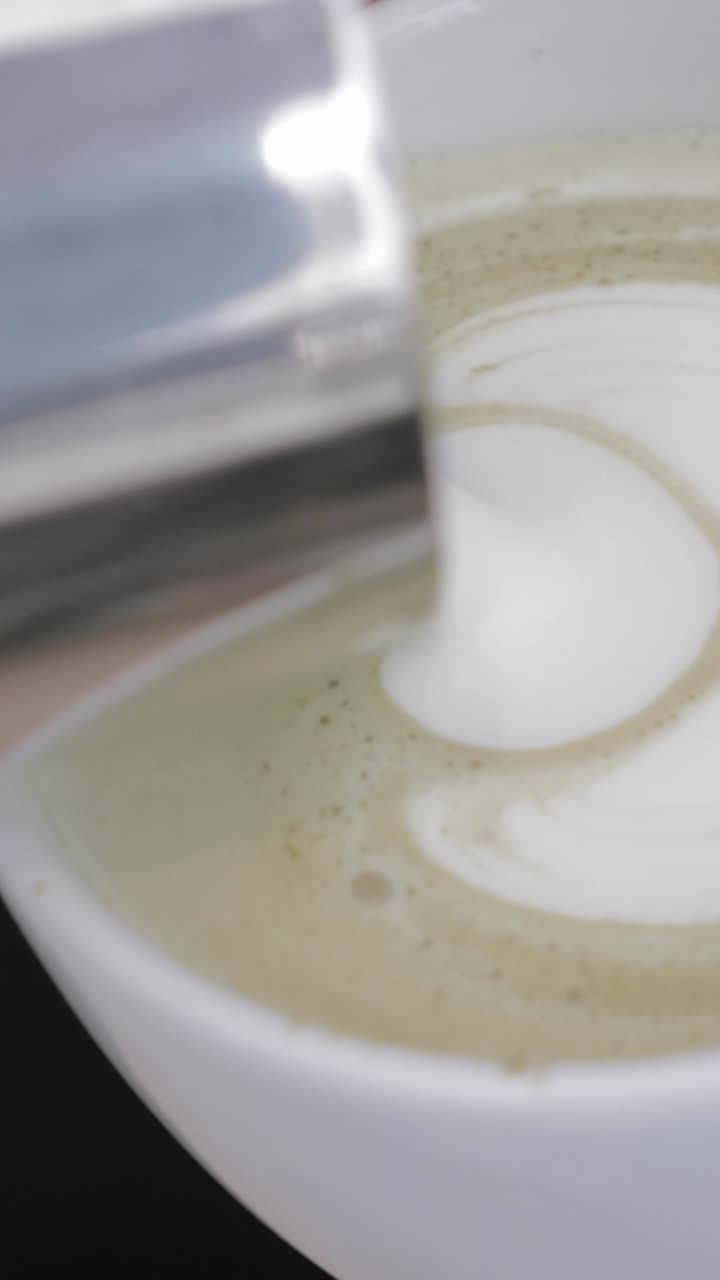 Vertiendo leche para crear arte latte de corazón en una bebida de matcha