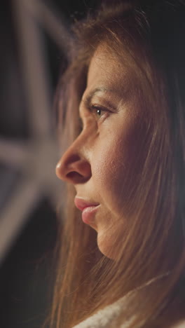 pensive woman with serious expression on face thinks about painful situations in dimly lit apartment room. lonely thinking and depression at twilight