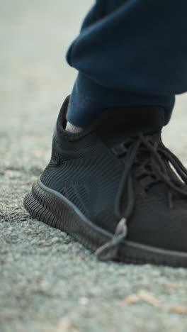 close-up view of someone in black sneakers and blue trousers moving their leg forward and backward with a blurred background